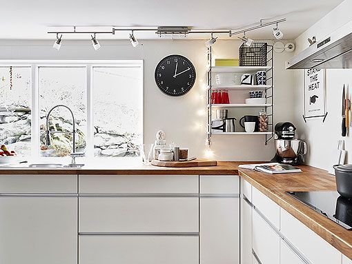 Parte del interior de una cocina moderna blanca con armarios con vidrio  esmerilado, una pared de ladrillo blanco y una encimera de madera. equipo  de cocina.