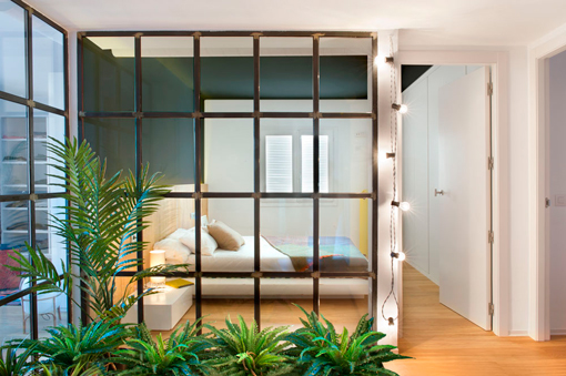 Reforma Integral: dormitorio con pared acristalada con perfiles metálicos