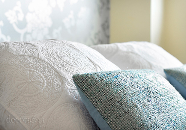 Dormitorio con textiles en tonos blancos y grises