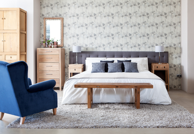 Dormitorio con cabecero de tela y funda nórdica blanca con cojines grises