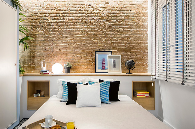 Dormitorio con pared de ladrillo y mueble de obra en el cabecero