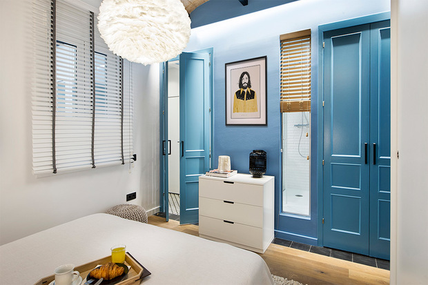 Dormitorio con pared azul y acceso a cuarto de baño
