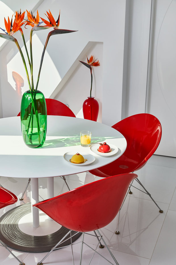 Comedor con mesa blanca acompañada de sillas rojas