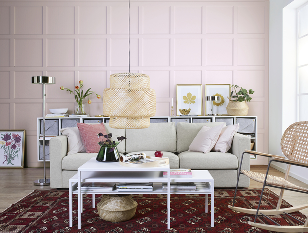 Salón con pared rosa y muebles blancos y de fibra